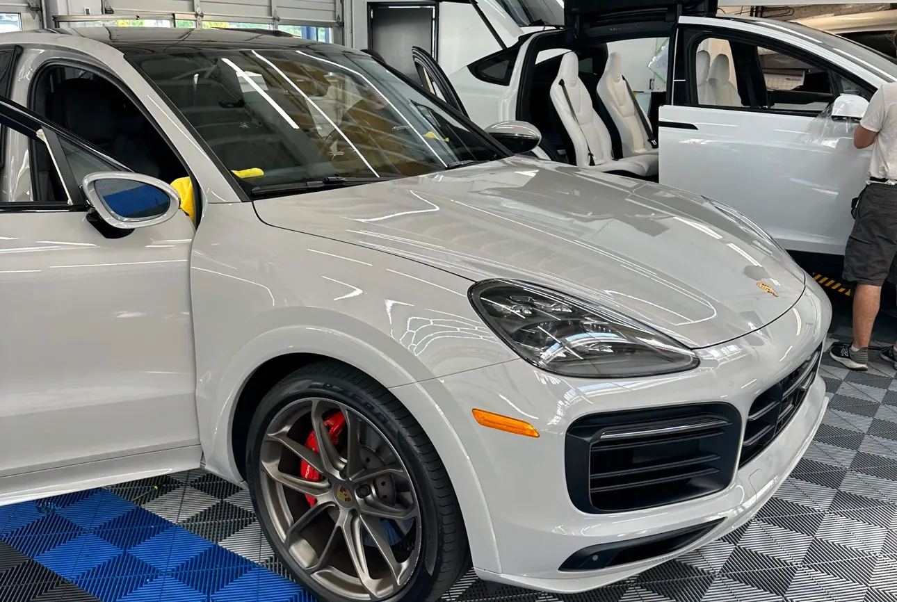 White Porsche Cayenne in the shop bay after full-front paint protection film